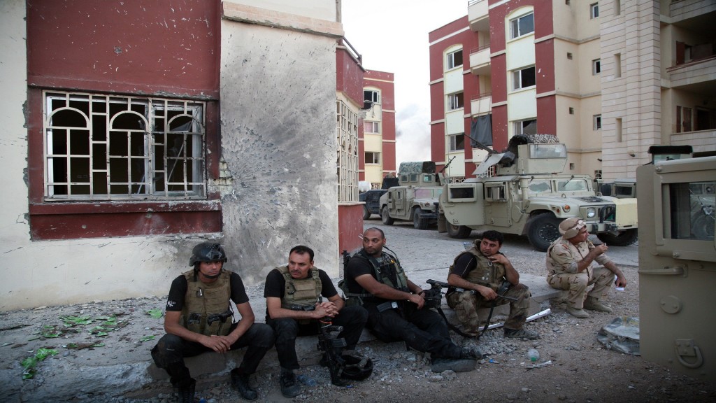 Iraqi security forces and gunmen rest on a sidewalk following clashes with jihadists on September 19, 2014, in Ramadi, the capital of the western province of Anbar. On September 17, a suicide car bomb destroyed a key bridge in Ramadi, a city west of Baghdad where the support of Sunni tribes is seen as vital to any nationwide fightback against the jihadists. AFP PHOTO/AZHAR SHALLAL        (Photo credit should read AZHAR SHALLAL/AFP/Getty Images)