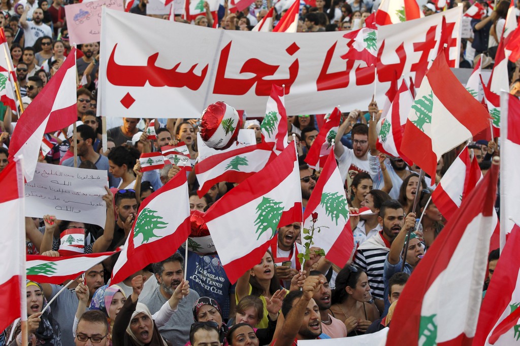 People carry Lebanese national flags and banners as they take part in an anti-government protest at Martyrs' Square in downtown Beirut, Lebanon August 29, 2015. Thousands of protesters waving Lebanese flags and chanting "revolution" took to the streets of Beirut on Saturday for an unprecedented mobilisation against sectarian politicians they say are incompetent and corrupt. REUTERS/Mohamed Azakir